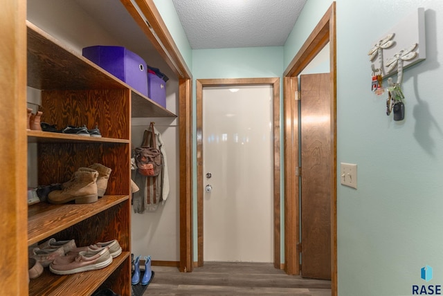 hall featuring wood finished floors, baseboards, and a textured ceiling