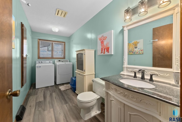 bathroom with vanity, wood finished floors, visible vents, toilet, and washer and clothes dryer