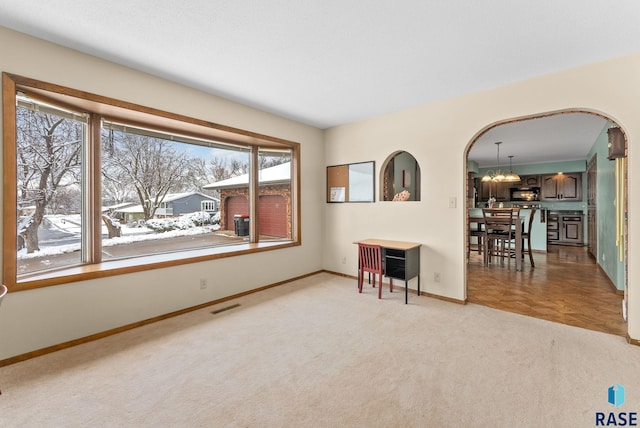 empty room featuring visible vents, baseboards, an inviting chandelier, arched walkways, and carpet flooring