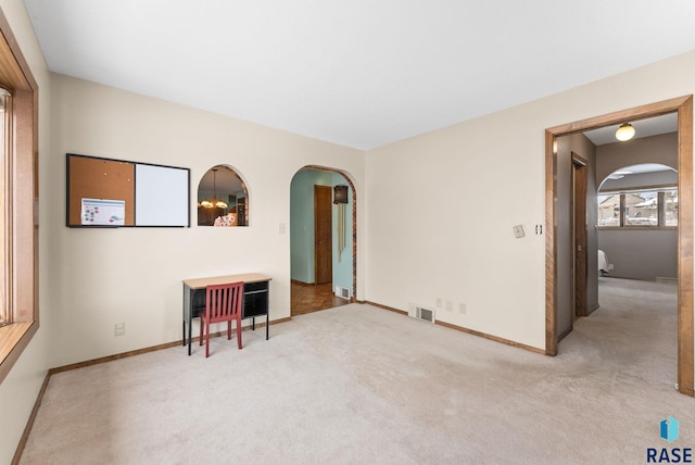 carpeted empty room with arched walkways, visible vents, and baseboards