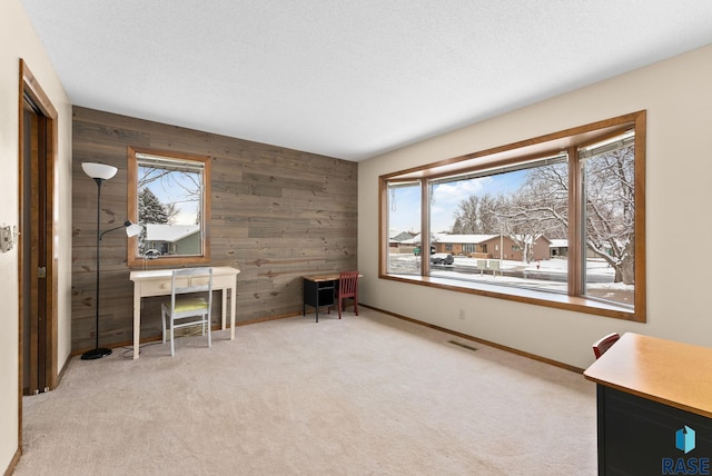 unfurnished office with visible vents, carpet floors, wooden walls, and a textured ceiling