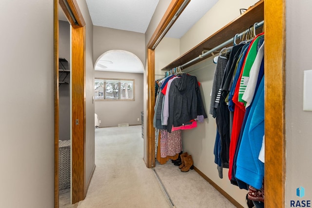 walk in closet with carpet and arched walkways