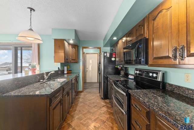 kitchen featuring appliances with stainless steel finishes, a peninsula, hanging light fixtures, a textured ceiling, and a sink