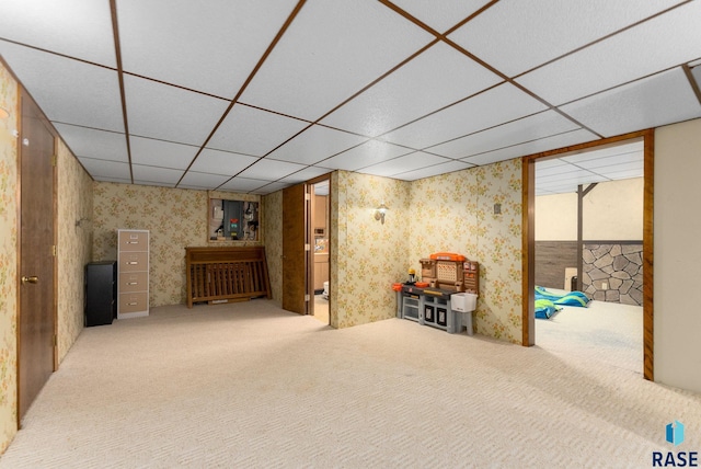 finished below grade area featuring wallpapered walls, carpet flooring, and a drop ceiling