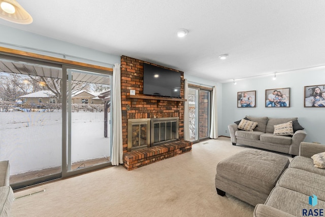 carpeted living room featuring visible vents, a healthy amount of sunlight, a brick fireplace, and a textured ceiling