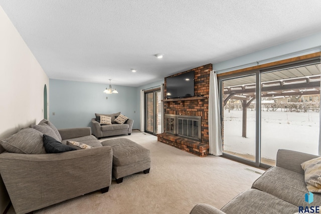 living room featuring visible vents, light carpet, a notable chandelier, a textured ceiling, and a brick fireplace