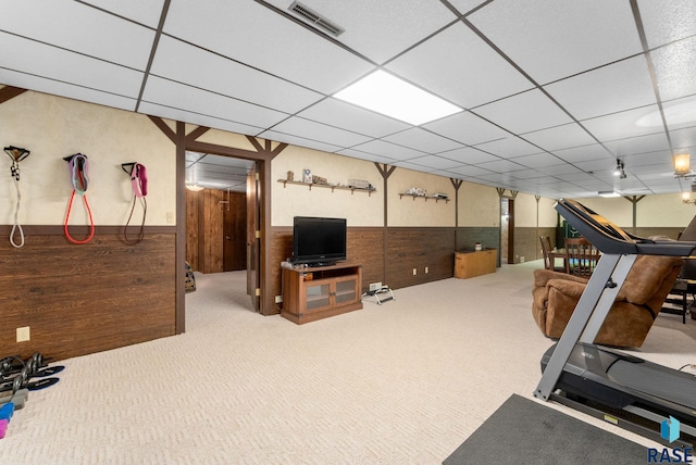 exercise area featuring a wainscoted wall, visible vents, a paneled ceiling, and wooden walls