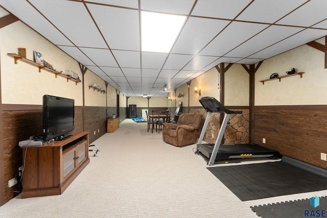 exercise room featuring a drop ceiling, carpet flooring, wood walls, and wainscoting