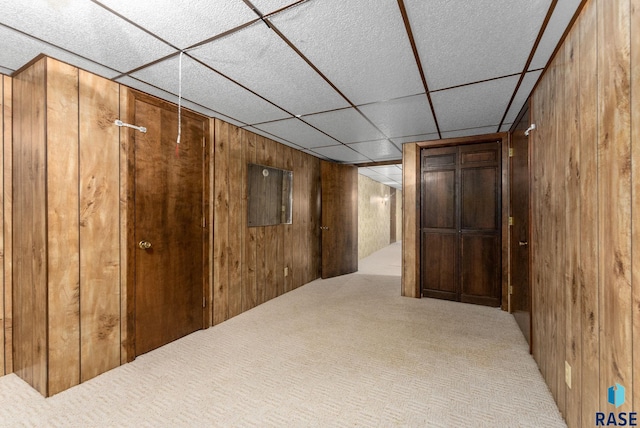 interior space featuring wood walls, a paneled ceiling, and carpet