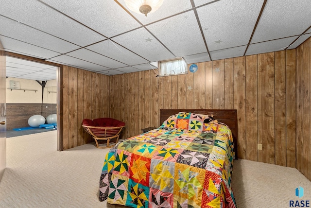 unfurnished bedroom with a drop ceiling, wooden walls, and carpet flooring