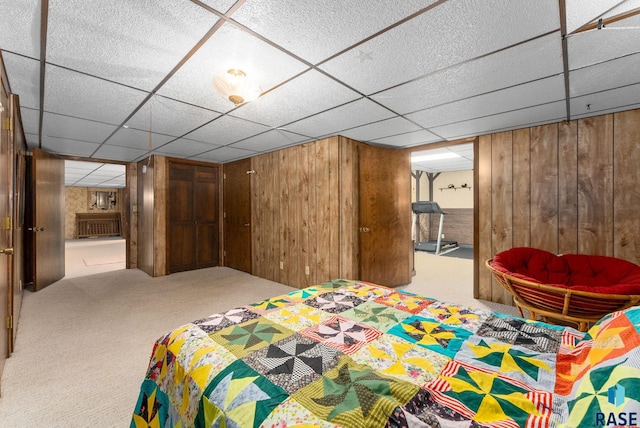 carpeted bedroom with wood walls and a paneled ceiling