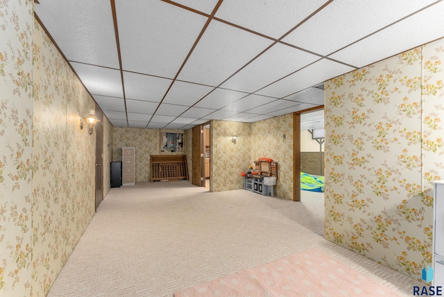 finished basement featuring a paneled ceiling, carpet, and wallpapered walls