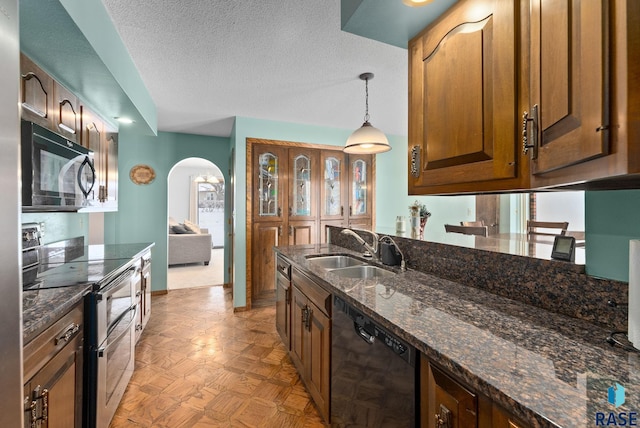 kitchen featuring black appliances, dark stone counters, arched walkways, a textured ceiling, and a sink