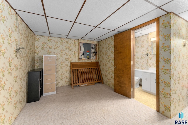 finished basement with a paneled ceiling, carpet flooring, and wallpapered walls