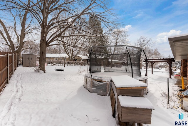 yard layered in snow featuring an outdoor structure, a pergola, a trampoline, and fence