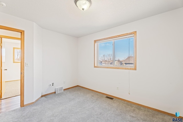 spare room with visible vents, baseboards, carpet, and a textured ceiling