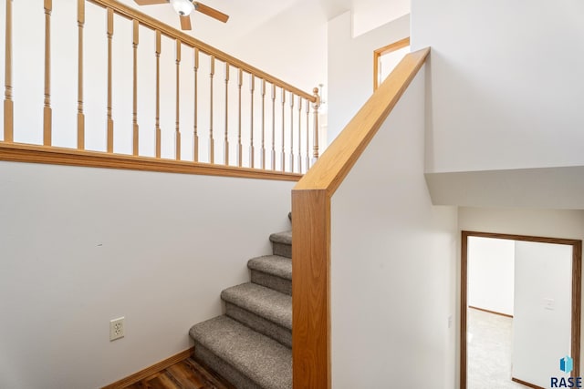 staircase with baseboards and ceiling fan