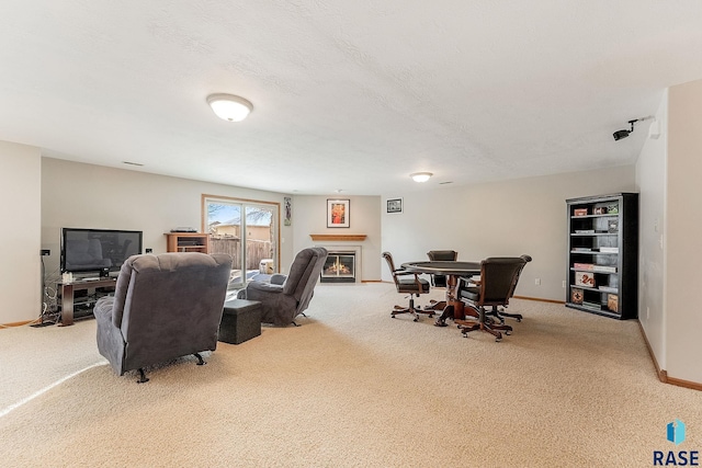 living room featuring a glass covered fireplace, carpet flooring, baseboards, and a textured ceiling