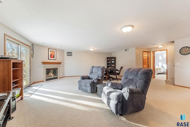 living area featuring baseboards, a fireplace with flush hearth, and light colored carpet