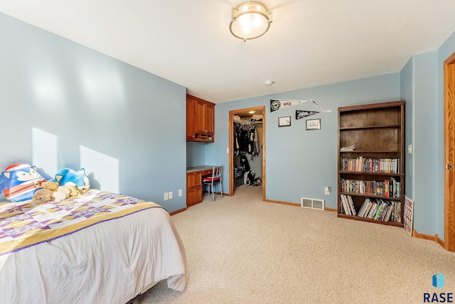 bedroom with visible vents, a walk in closet, baseboards, light colored carpet, and a closet