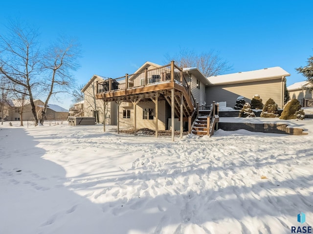 snow covered property with a deck, stairs, and a hot tub