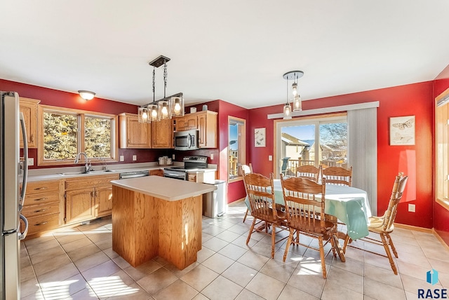 kitchen with light tile patterned floors, a sink, light countertops, appliances with stainless steel finishes, and a center island