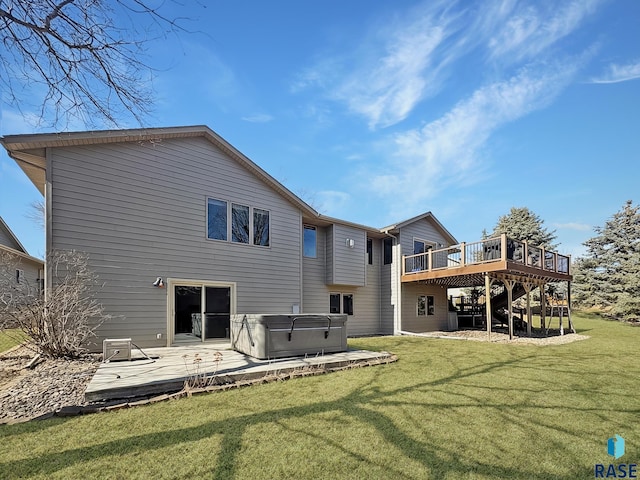 rear view of property with a yard, a hot tub, and a deck