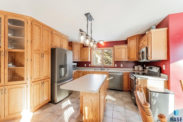 kitchen with a sink, a kitchen island, stainless steel appliances, light tile patterned flooring, and light countertops