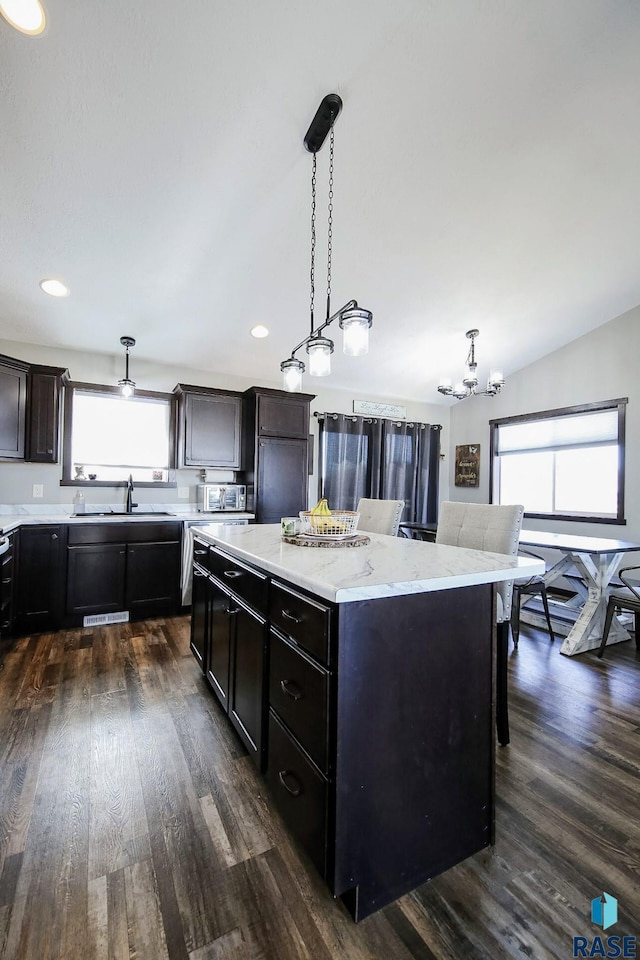 kitchen with hanging light fixtures, a center island, a healthy amount of sunlight, and a sink