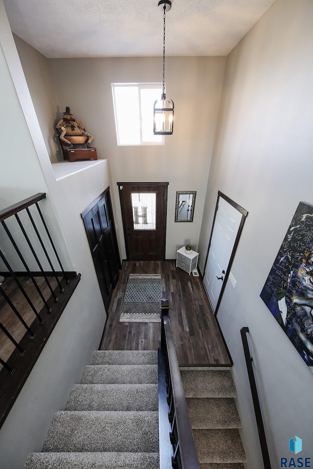 staircase with wood finished floors and a towering ceiling