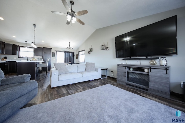 living room with recessed lighting, ceiling fan with notable chandelier, dark wood-type flooring, and vaulted ceiling