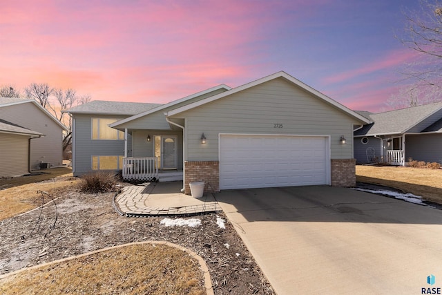 single story home featuring driveway, brick siding, covered porch, and an attached garage