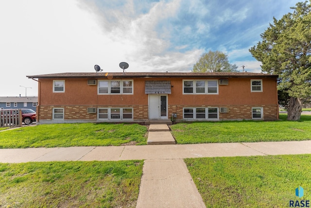 split foyer home with brick siding and a front lawn