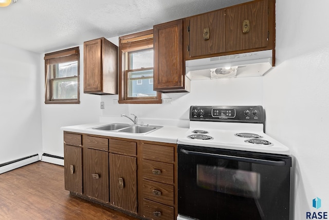 kitchen with under cabinet range hood, light countertops, range with electric stovetop, dark wood-style floors, and a sink