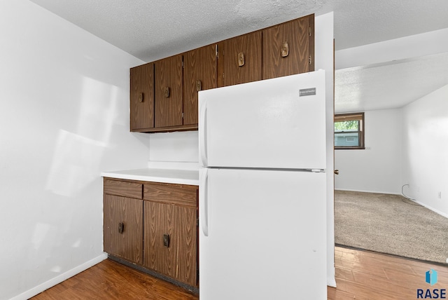 kitchen featuring wood finished floors, freestanding refrigerator, and a textured ceiling