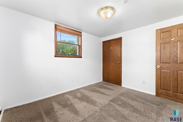 unfurnished bedroom featuring a textured ceiling, baseboards, and carpet