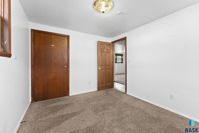 unfurnished bedroom with a closet, a textured ceiling, baseboards, and carpet floors