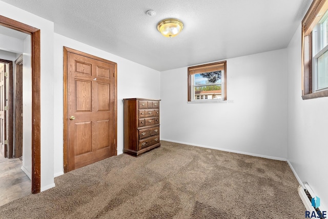 unfurnished bedroom featuring baseboards, carpet floors, baseboard heating, and a textured ceiling