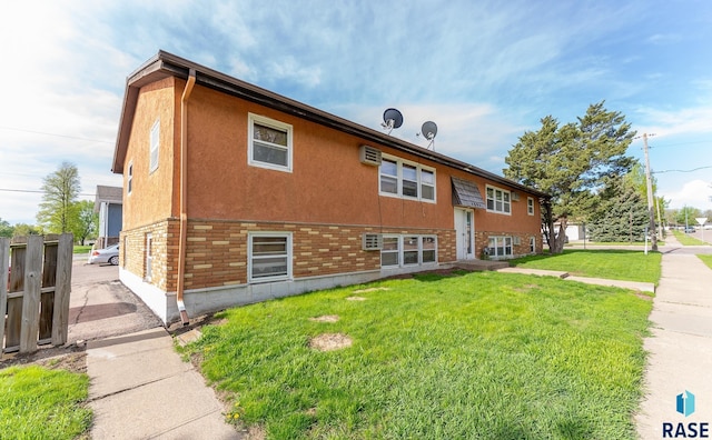 exterior space featuring a yard, fence, brick siding, and stucco siding