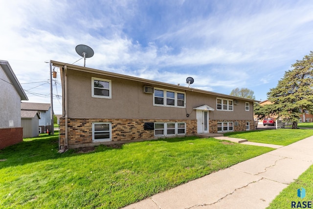 split foyer home with stucco siding, brick siding, and a front lawn