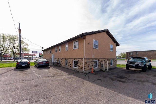 view of side of property featuring brick siding, stucco siding, and uncovered parking