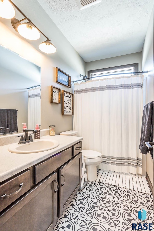 bathroom featuring vanity, tile patterned floors, toilet, and a textured ceiling