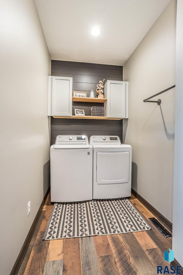 laundry area with visible vents, baseboards, wood finished floors, cabinet space, and separate washer and dryer