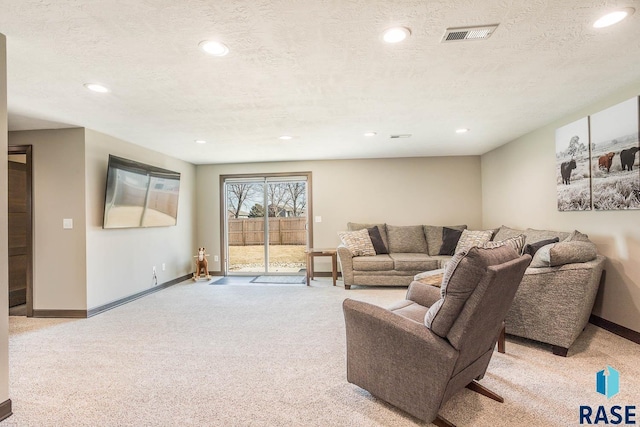 living room featuring recessed lighting, light colored carpet, and a textured ceiling