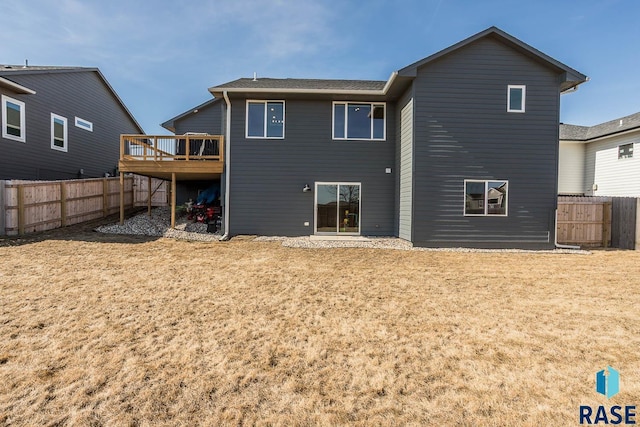 back of house featuring a deck, a fenced backyard, and a lawn