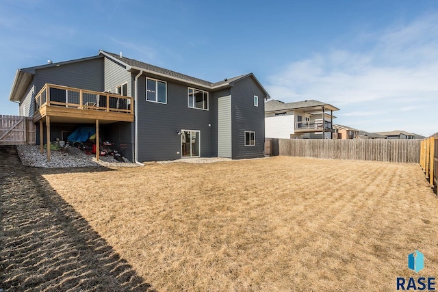 back of house featuring a wooden deck, a lawn, and a fenced backyard