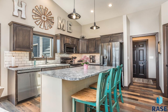 kitchen featuring a sink, a center island, stainless steel appliances, dark brown cabinetry, and light countertops