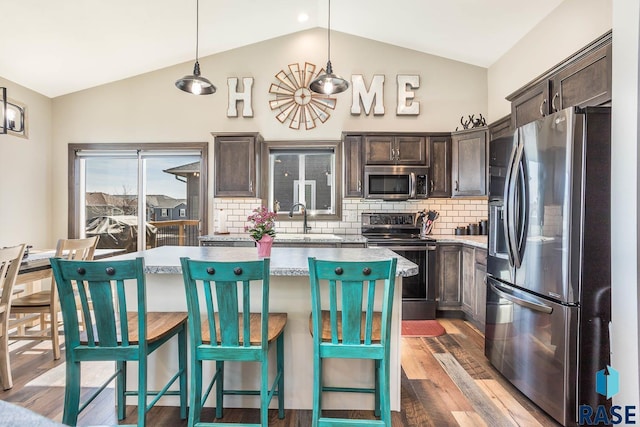 kitchen featuring dark brown cabinets, a kitchen island, dark wood-type flooring, lofted ceiling, and stainless steel appliances