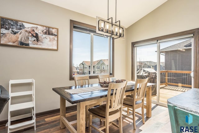 dining space with plenty of natural light, a notable chandelier, lofted ceiling, and wood finished floors