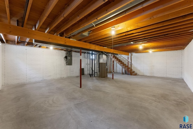 unfinished basement featuring electric panel and brick wall